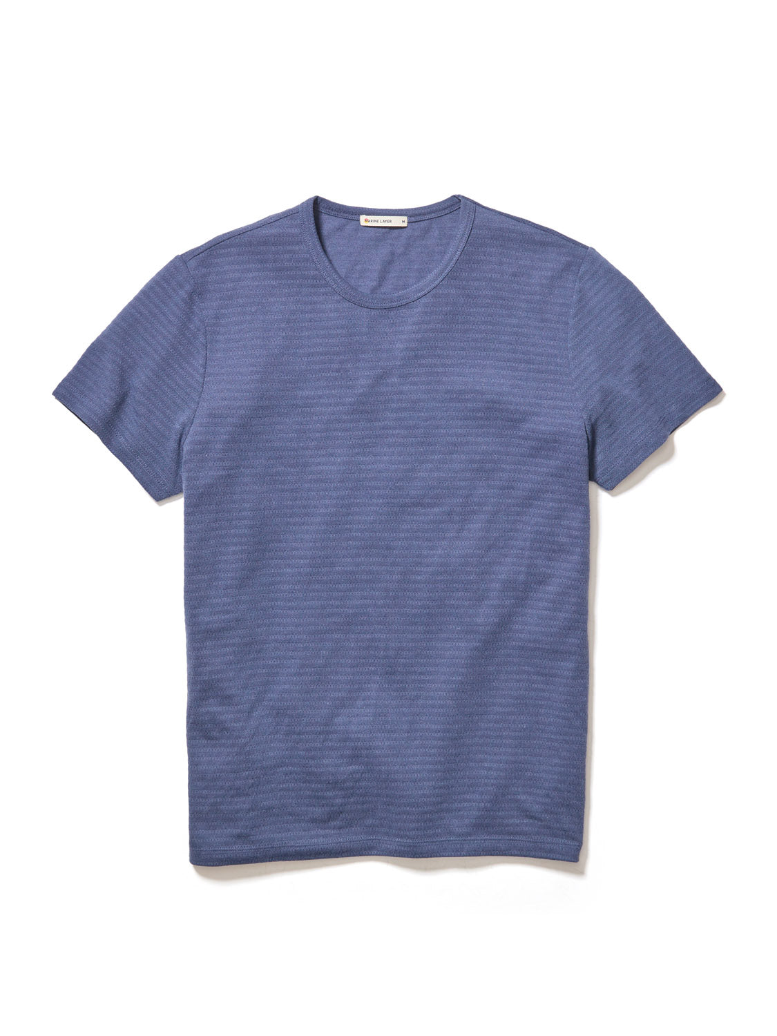 The Marine Layer Signature Jacquard Crew Tee, from Marine Layer, is a blue crew shirt with a subtle textured pattern. It features short sleeves, is crafted from recycled polyester, and showcases sustainability and style against a white background.