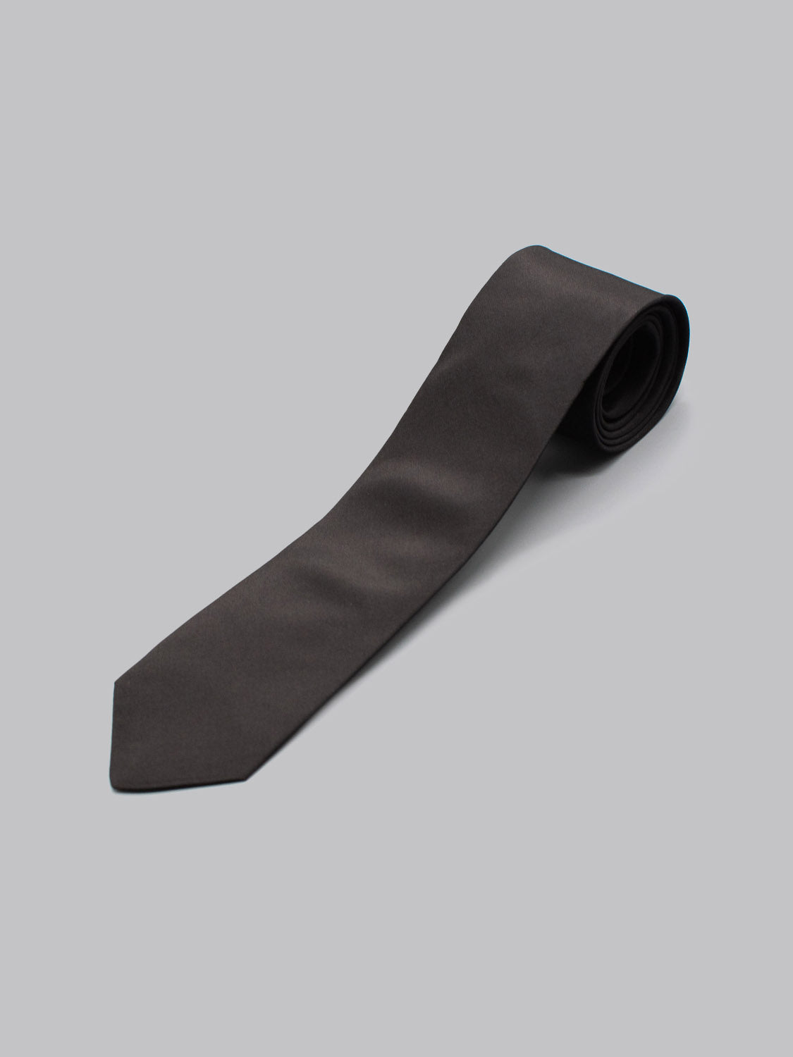 The ID Silk Taffeta Tie by ID Menswear is a neatly rolled black necktie with a pointed end, crafted from luxurious English silk, and displayed on a plain light gray background.