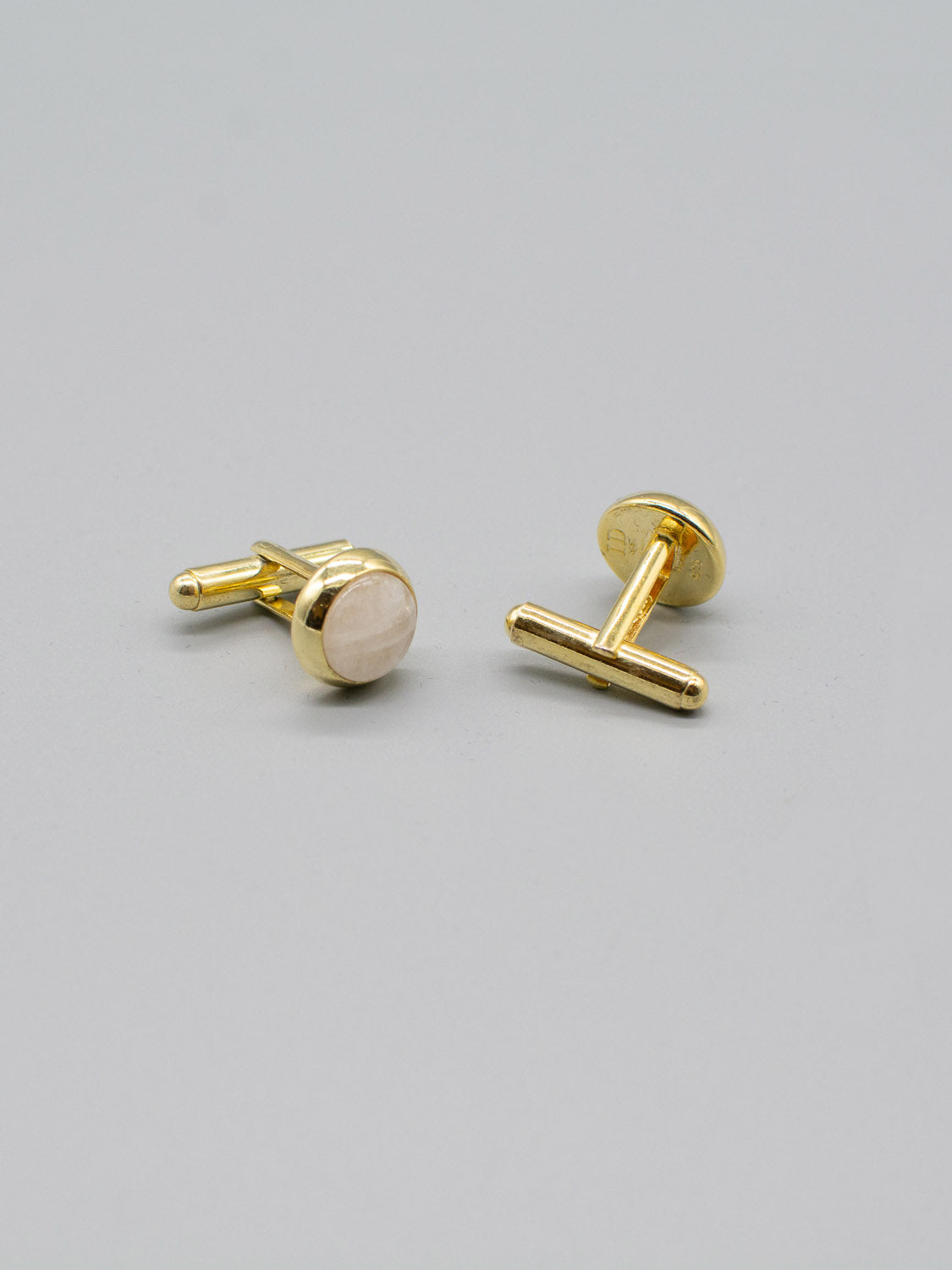 The ID Menswear Gold Plated Silver Gemstone Cufflinks, featuring round light-colored stones and a polished finish, are displayed on a gray background. Positioned at slight angles to each other, they showcase their elegant gemstone inlay with a bullet back mechanism.