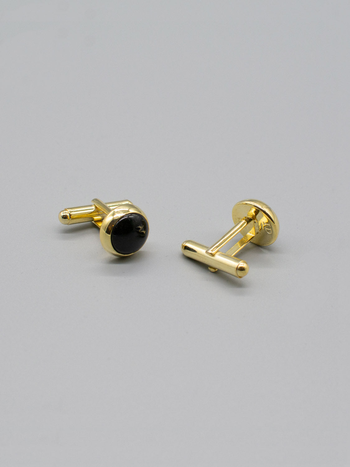 ID Menswears Gold Plated Silver Gemstone Cufflinks feature black oval gems contrasting with a light gray backdrop. One cufflink displays the front, while the other is shown sideways, highlighting its bullet back mechanism.