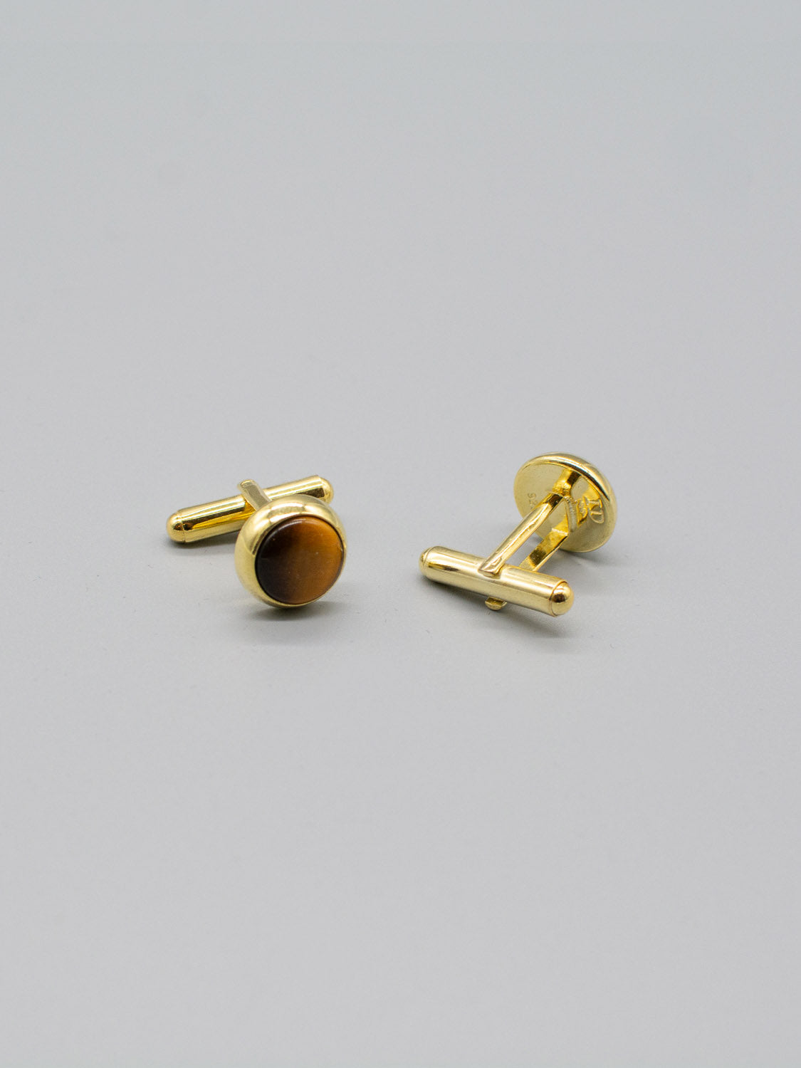 A pair of elegant ID Menswear Gold Plated Silver Gemstone Cufflinks features round, polished brown stones and a sleek bullet back on a light gray background.