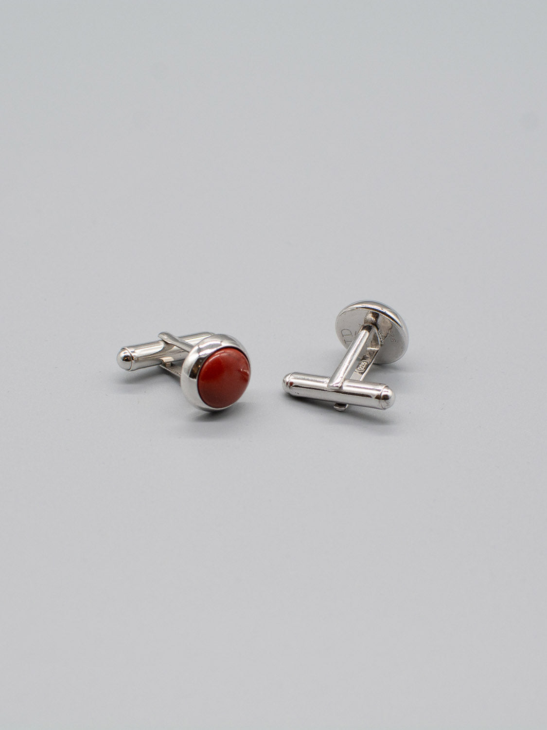 A pair of Silver Gemstone Cufflinks by ID Menswear, featuring round red stones with a striking gemstone inlay set against a simple gray background.