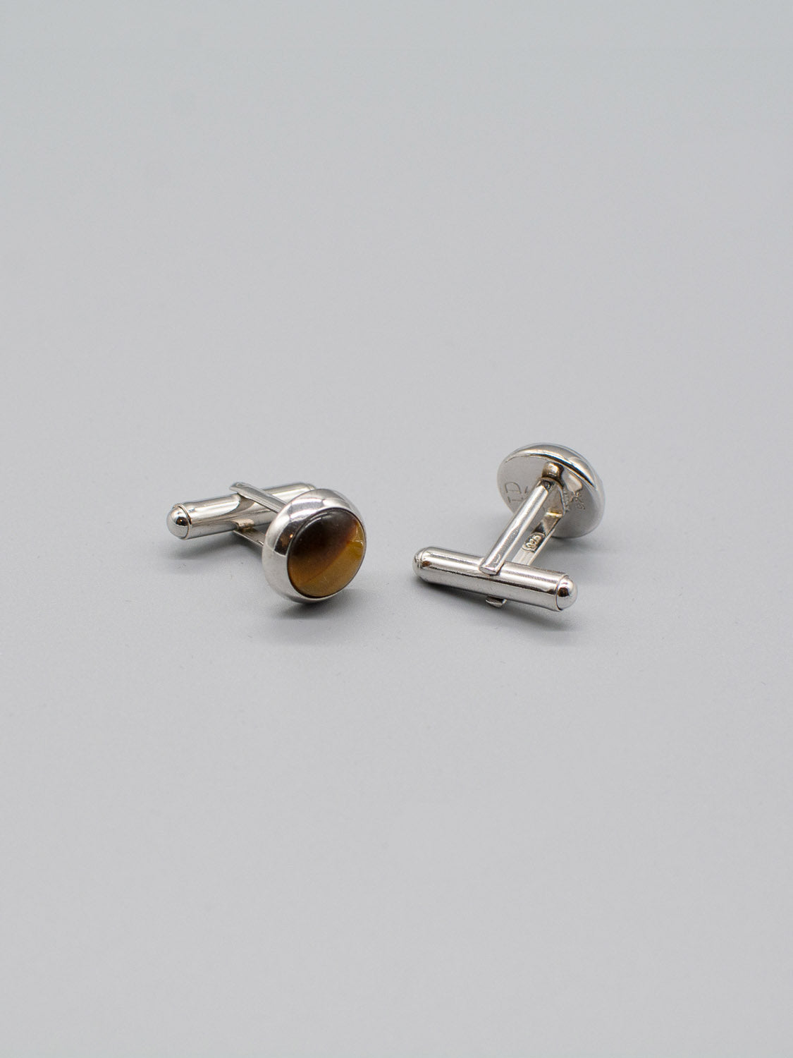Two Rhodium Plated Silver Gemstone Cufflinks by ID Menswear are on a light gray background. One is upright; the other lies on its side, highlighting the T-bar fastening and genuine gemstone inlay.