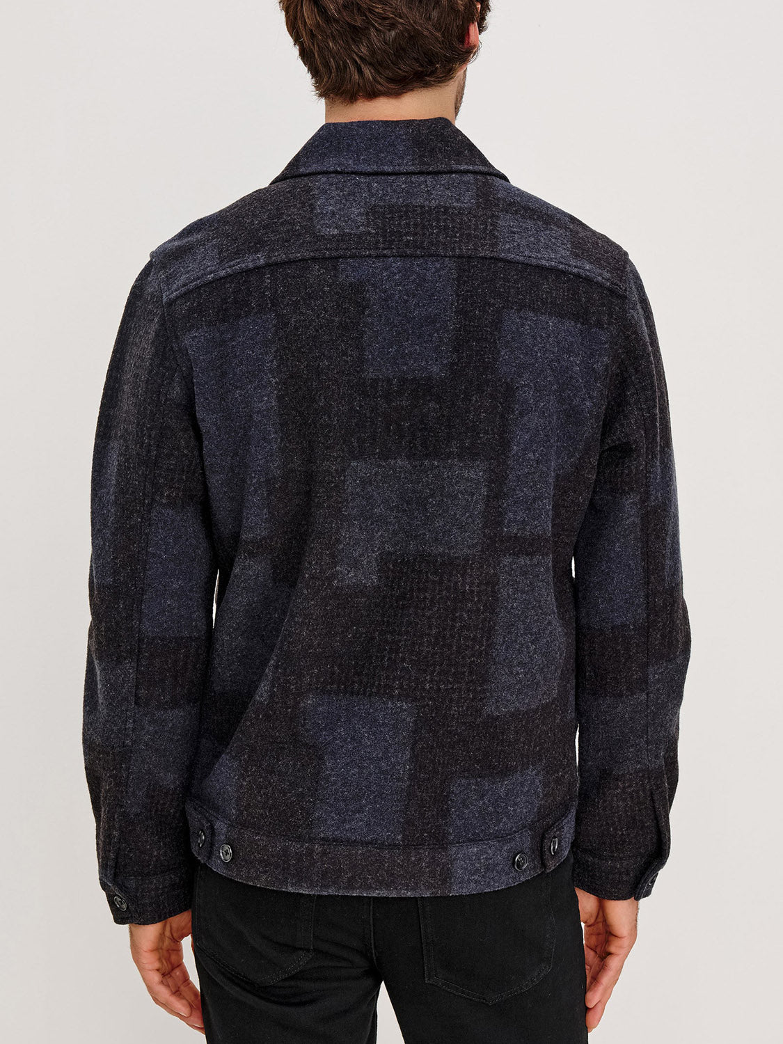 A person is seen from behind wearing the Rails Simon Jacket, a dark blue and black checkered wool blend, paired with black pants against a plain light background.