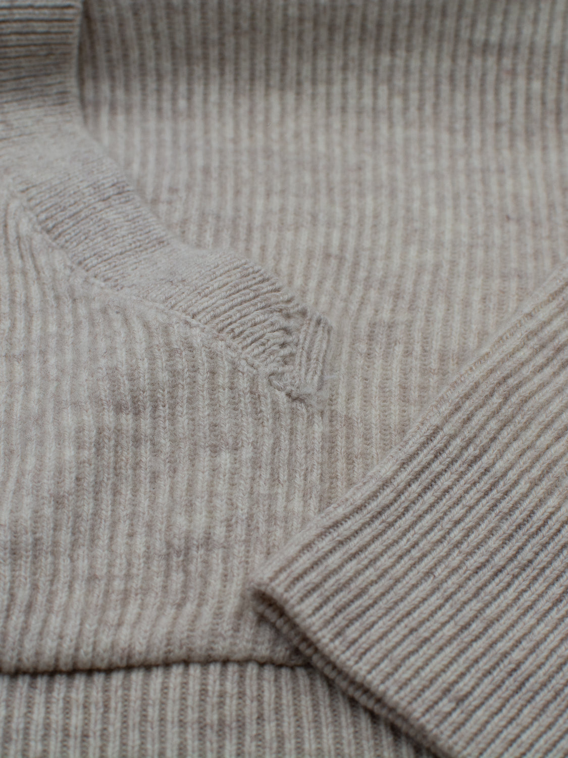 Close-up of the ID Menswear Skien Merino Wool Hoody’s beige ribbed knit fabric, highlighting detailed stitching near the sleeve and body seam—an ideal cold-weather wardrobe addition.