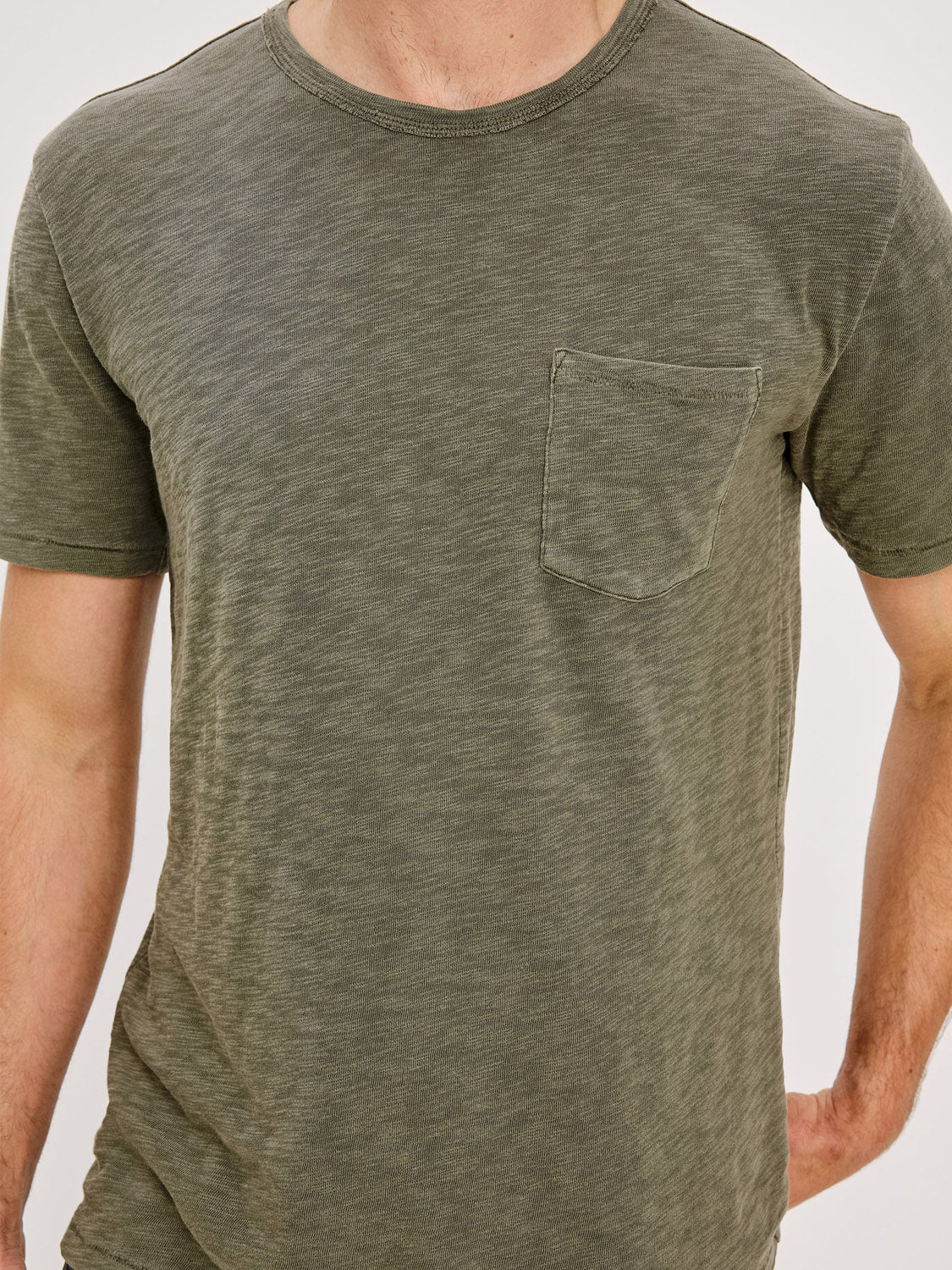 A person wears the Rails Skipper T-Shirt, a short-sleeve, olive green vintage wash tee with a round neckline and small chest pocket, shown from shoulders to waist against a plain background.