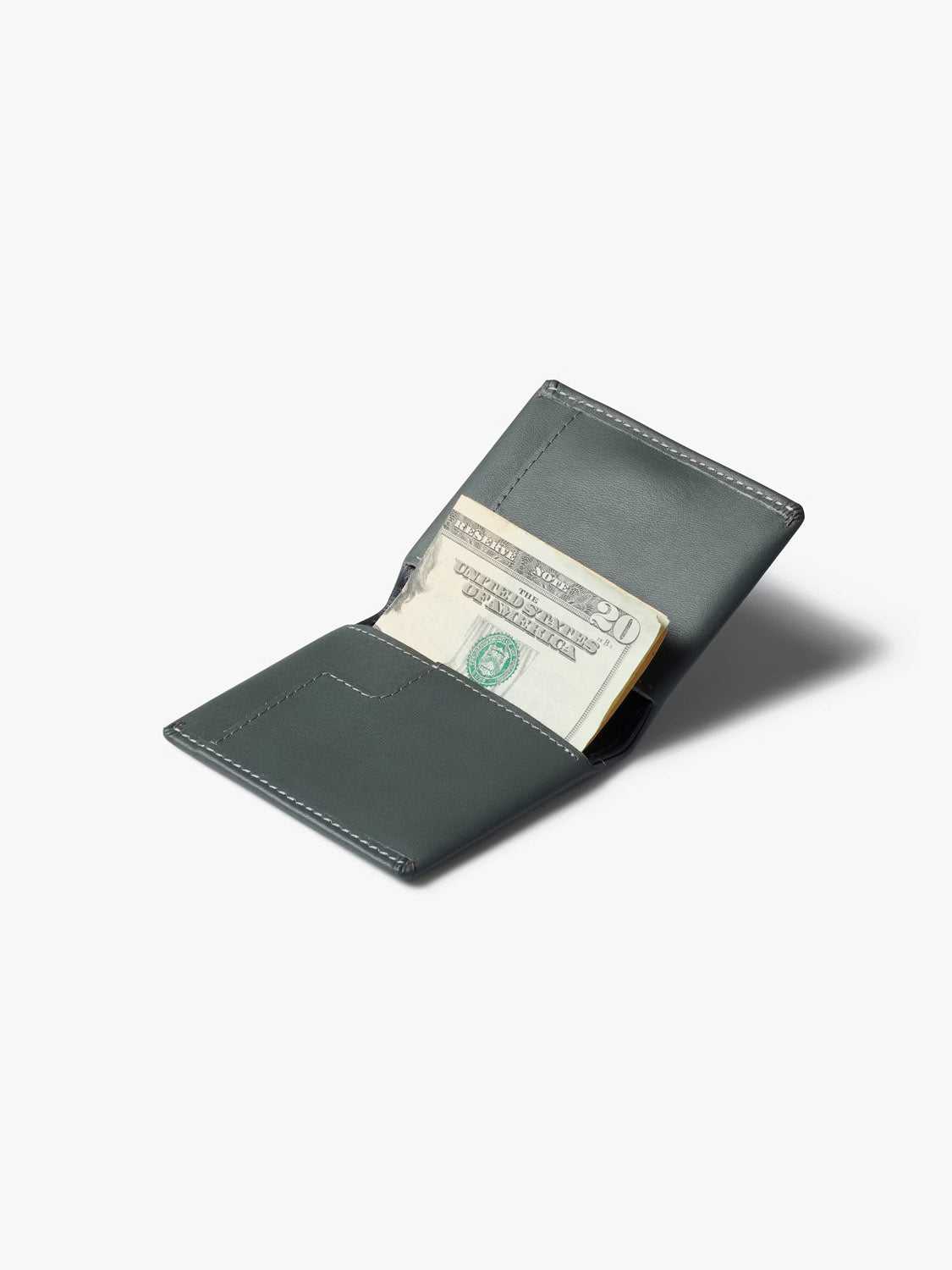 The Bellroy Slim Sleeve Wallet in dark gray is open on a white background, showing a folded twenty-dollar bill inside.