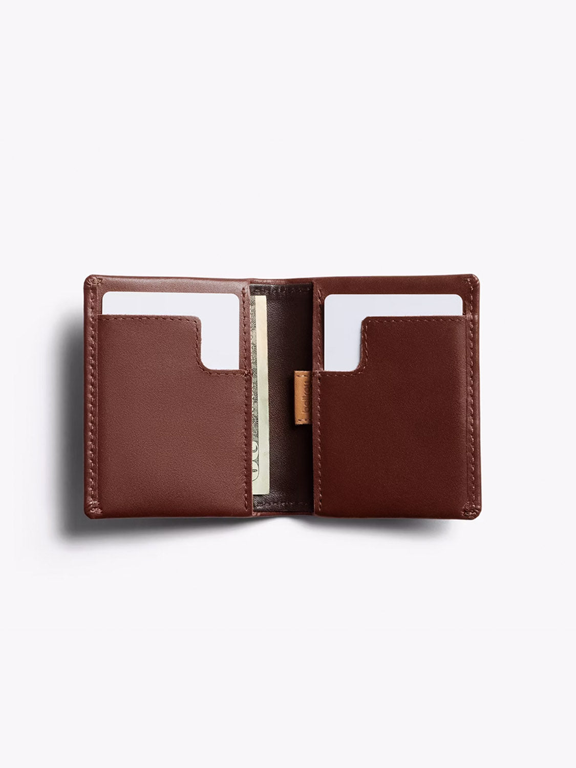 The Bellroy Slim Sleeve Wallet, crafted in open brown leather with compartments for cards and cash, is shown on a light background. The slim, pocket-friendly wallet displays two cards and a partially visible banknote.