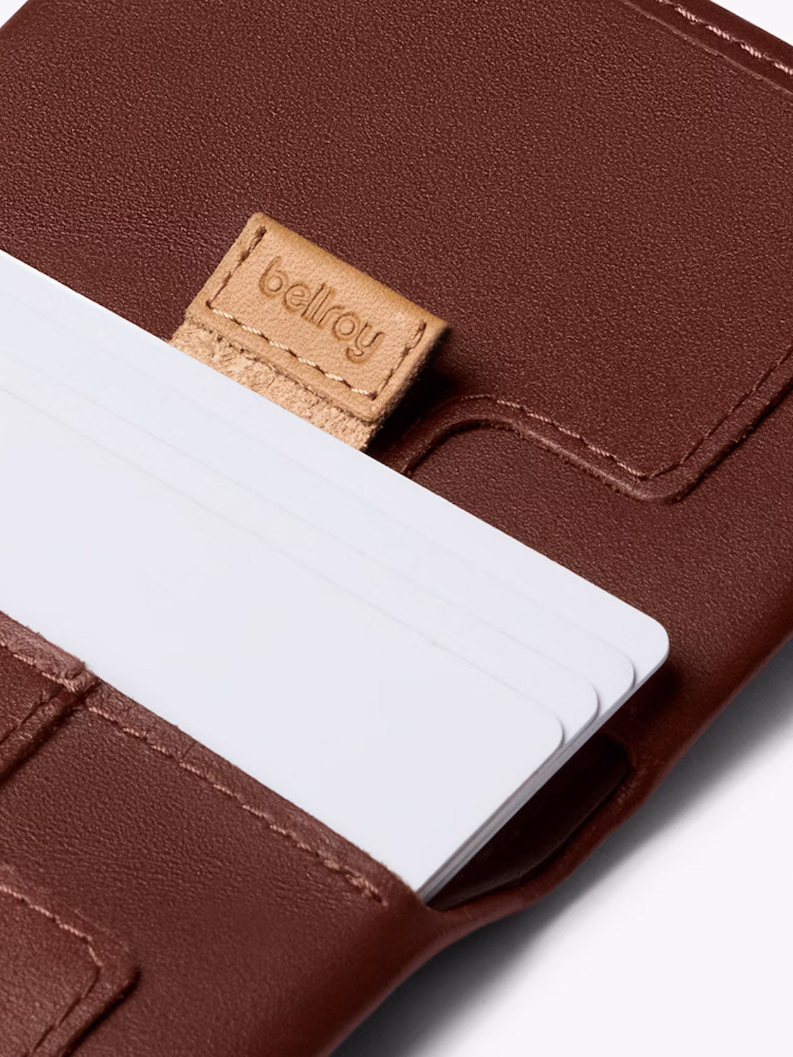 A close-up of the Bellroy Slim Sleeve Wallet, a brown leather cardholder featuring a tan Bellroy label and neatly organized white cards—an ideal, pocket-friendly wallet for daily essentials.