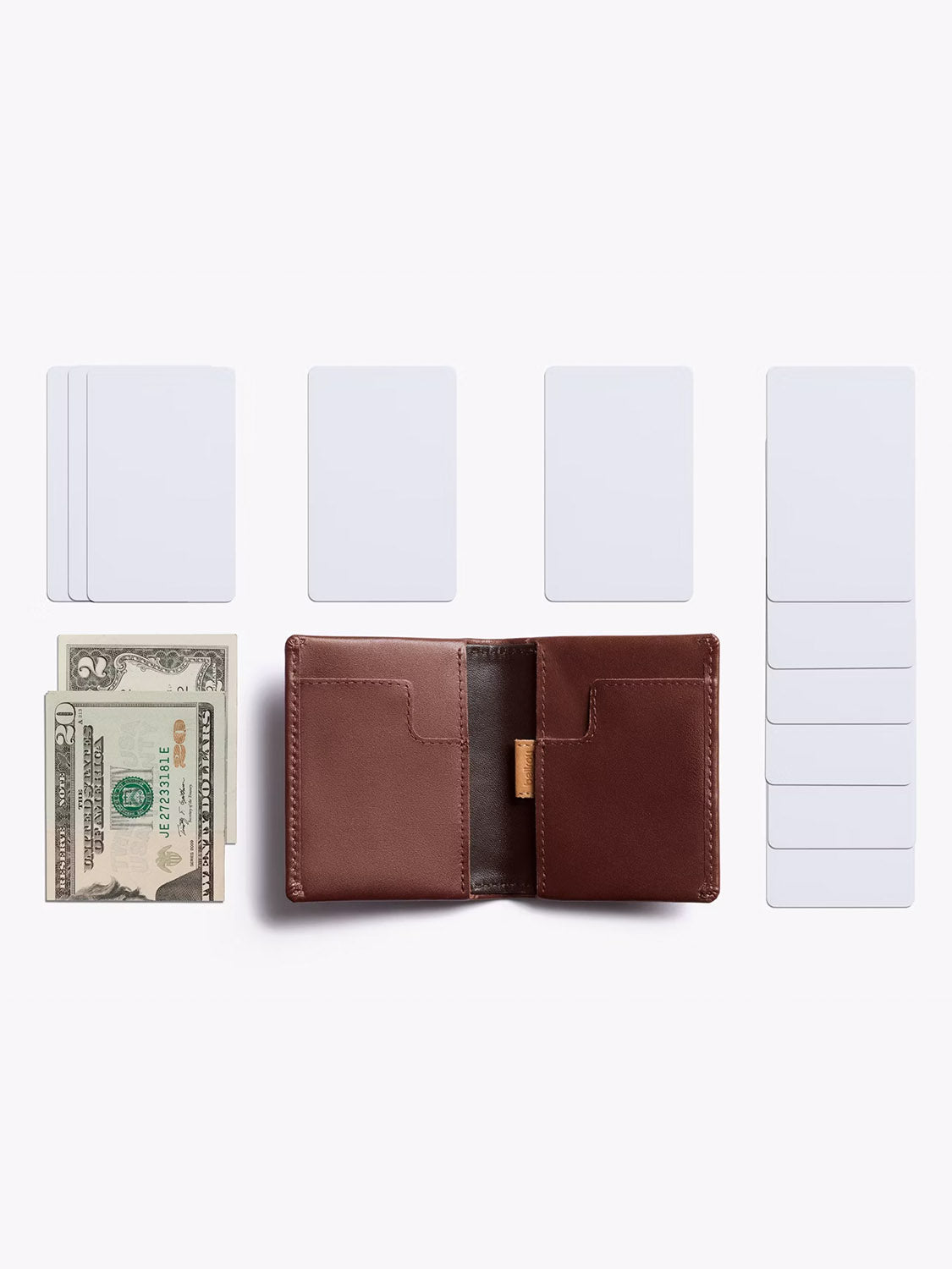 The Bellroy Slim Sleeve Wallet in brown leather is open on a white surface, showing cash inside. Several blank white cards are grouped around this compact, pocket-friendly wallet.