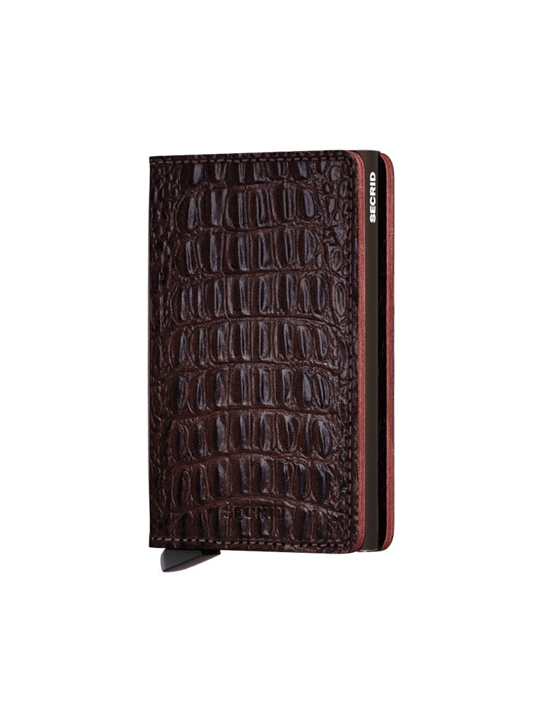 The Secrid Slimwallet Nile is a dark brown RFID wallet with a crocodile skin texture, a slim design, and the SECRID logo on the top right corner.