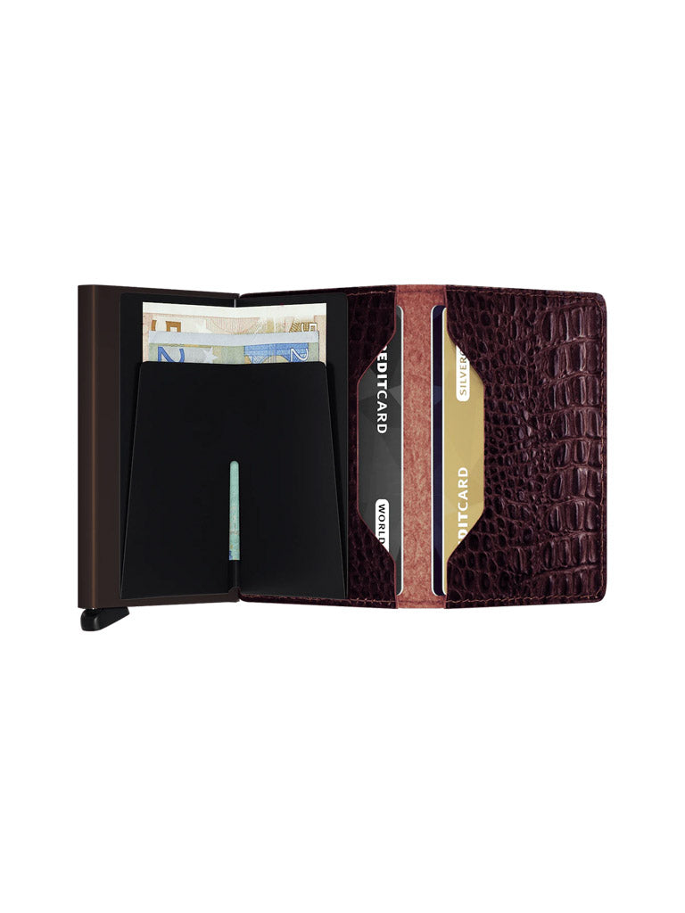The Secrid Slimwallet Nile, featuring a dark brown crocodile pattern and RFID protection, is shown open against a white background with euro banknotes and credit cards organized neatly in its slots.