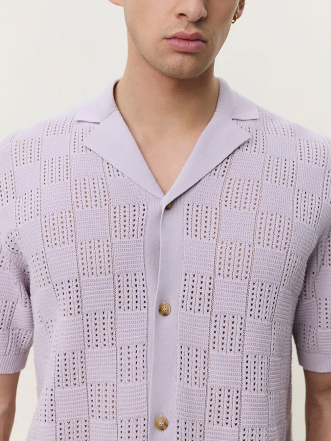A person wearing the Les Deux Squared Knitted SS Shirt—a light purple, short-sleeve cotton knit with checkerboard texture and spread collar—photographed from shoulders to mid-chest.