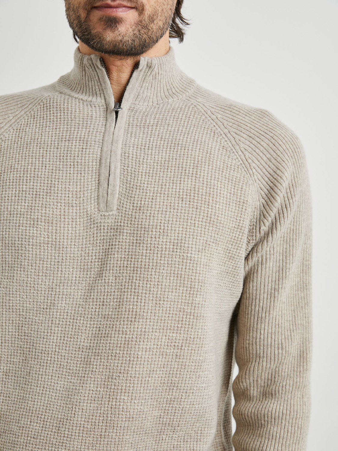 Someone is wearing the Rails Stark Quarter Zip Sweater, a light beige, ribbed-knit pullover with a half-zip collar. Its perfect for layering, emphasizing its texture and versatility on the upper body.
