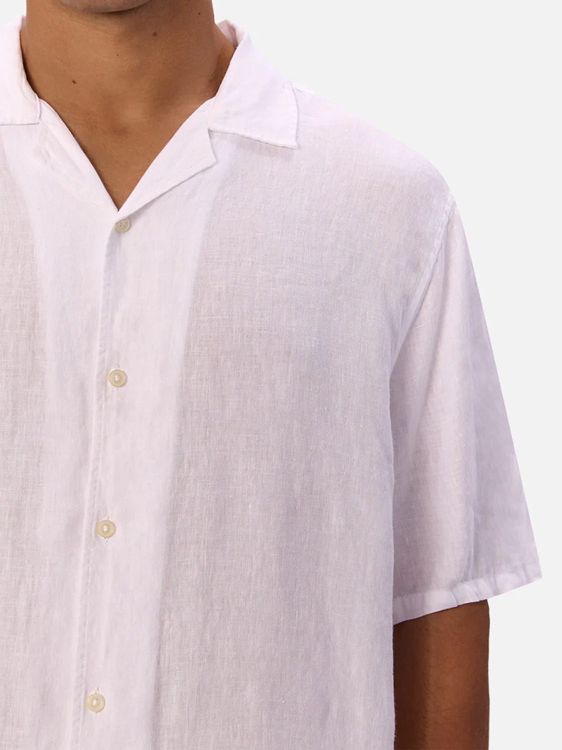 A person wears the Industrie St Martins Short Sleeve Shirt—a white, collared, button-up linen top with a smart casual look. The breathable fabric covers the upper torso and part of the arm.
