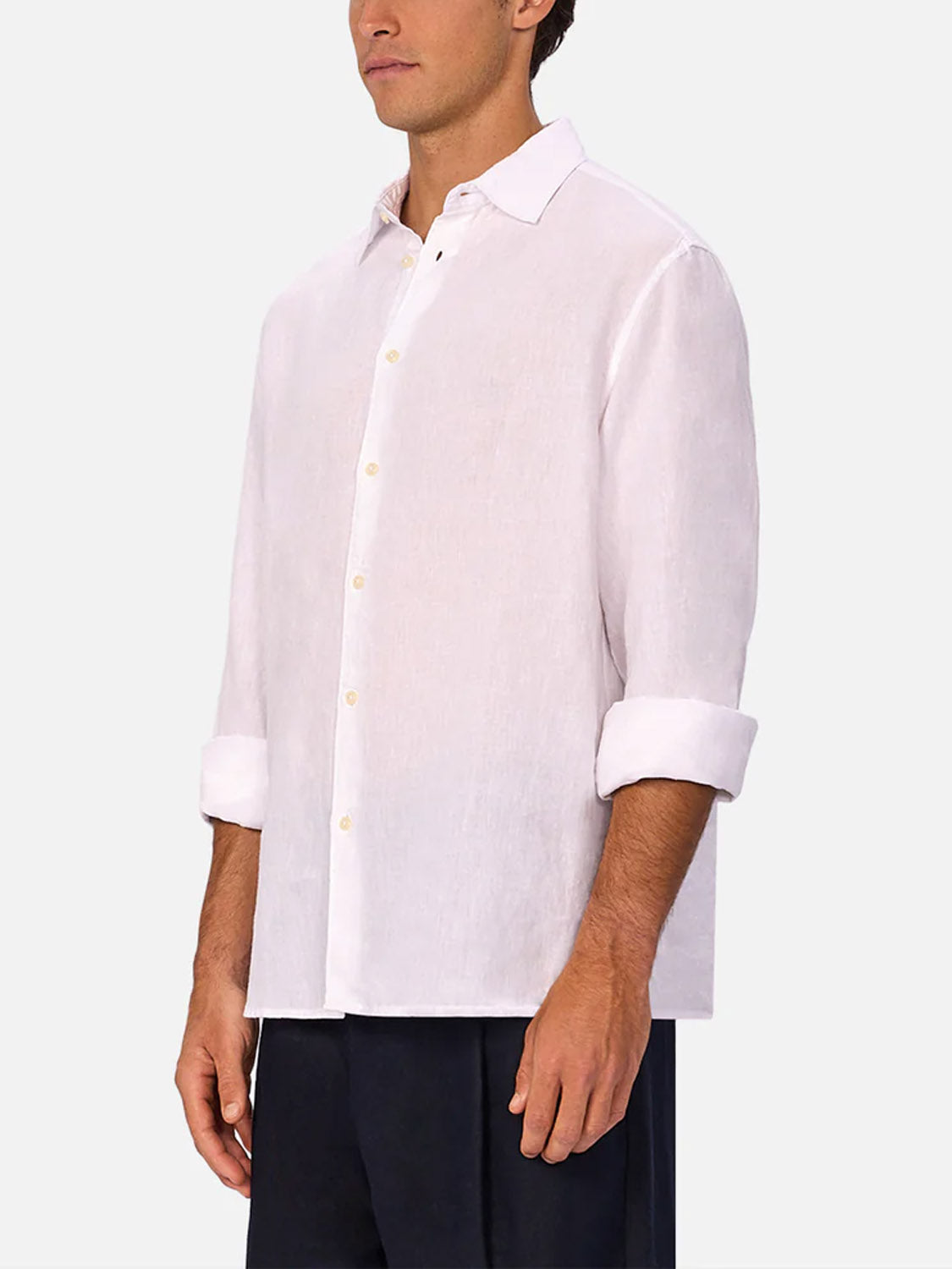 A man wears Industrie’s The St Martins Long Sleeve Shirt in light pink, sleeves rolled up, with dark pants against a plain background for a smart casual look.