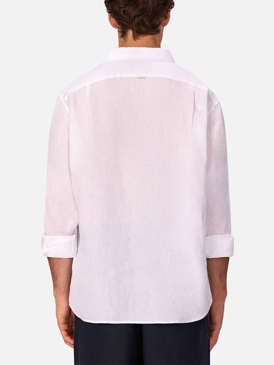 Seen from behind, a person wears the Industrie St Martins Long Sleeve Shirt—slightly sheer, untucked, and sleeves rolled up—with dark pants. The smart casual shirt stands out against a plain, light background.