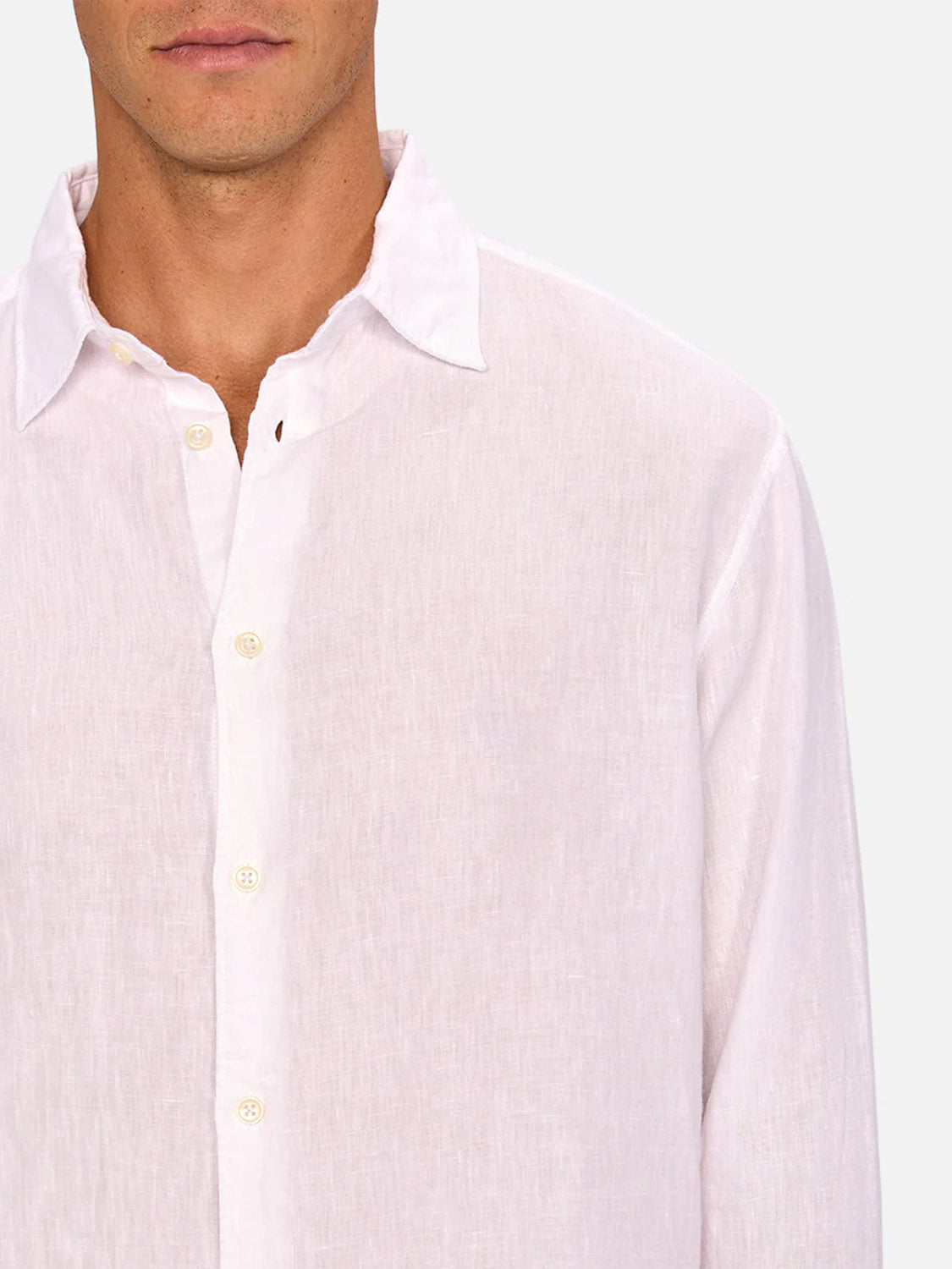 A man wears The St Martins Long Sleeve Shirt by Industrie in light pink linen, shown from the shoulders up against a plain background. Only the lower half of his face is visible, highlighting the shirt’s effortless smart-casual style.