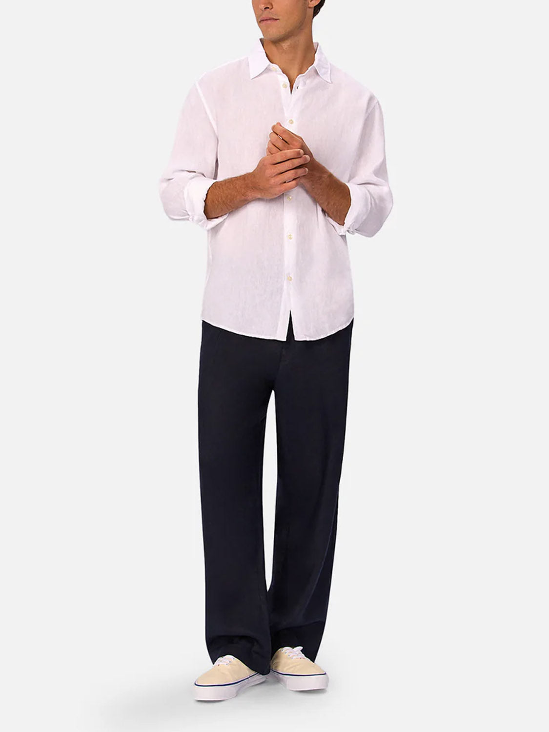 A man wears the Industrie St Martins Long Sleeve Shirt with loose dark pants and light sneakers, standing against a plain background with his hands clasped and head slightly turned.