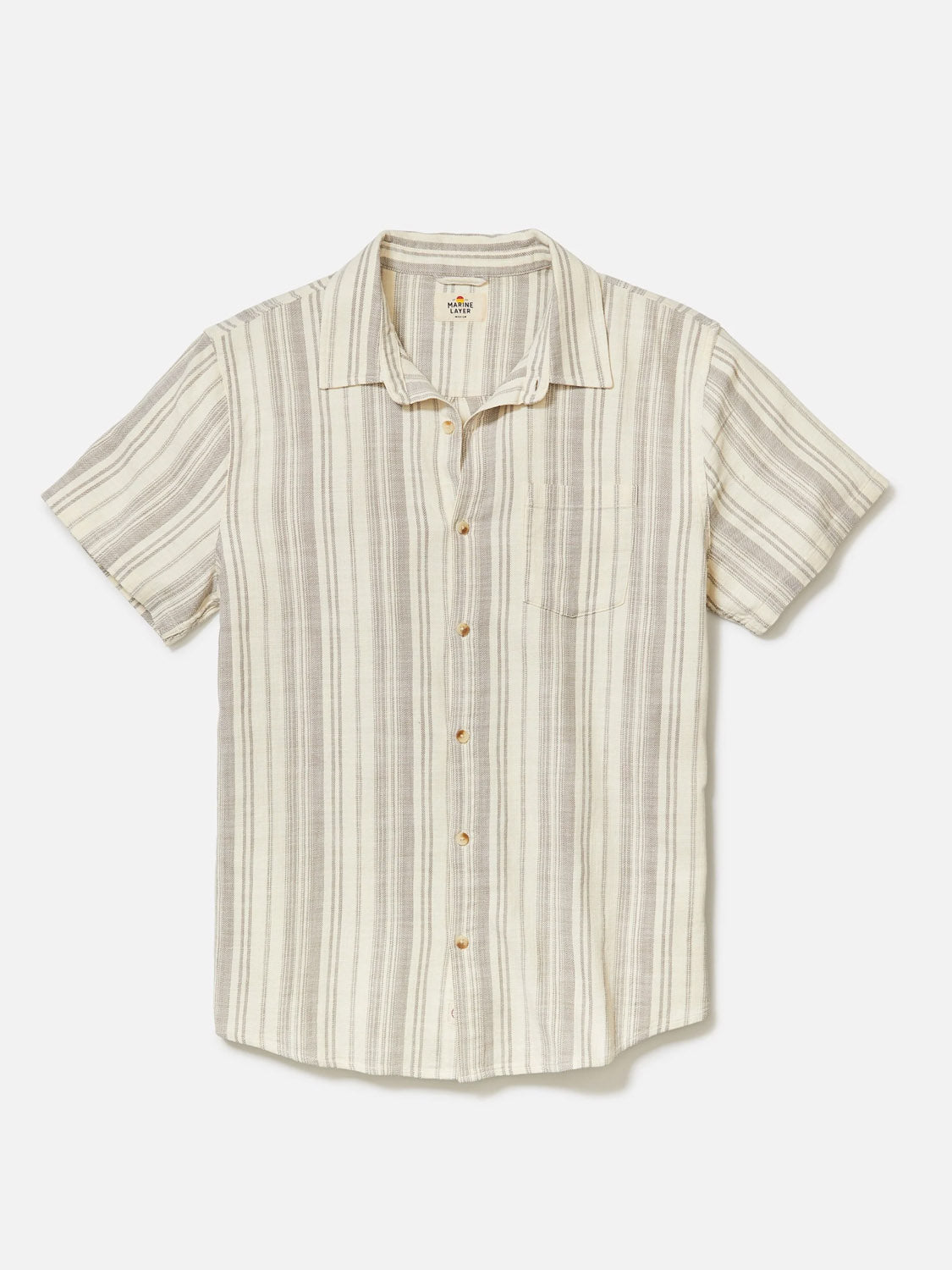 The Marine Layer Stretch Selvage Short Sleeve Shirt by Marine Layer is a short-sleeve, button-up shirt with beige, white, and gray vertical stripes in a classic fit. It features a small left chest pocket and is laid flat on a white background.