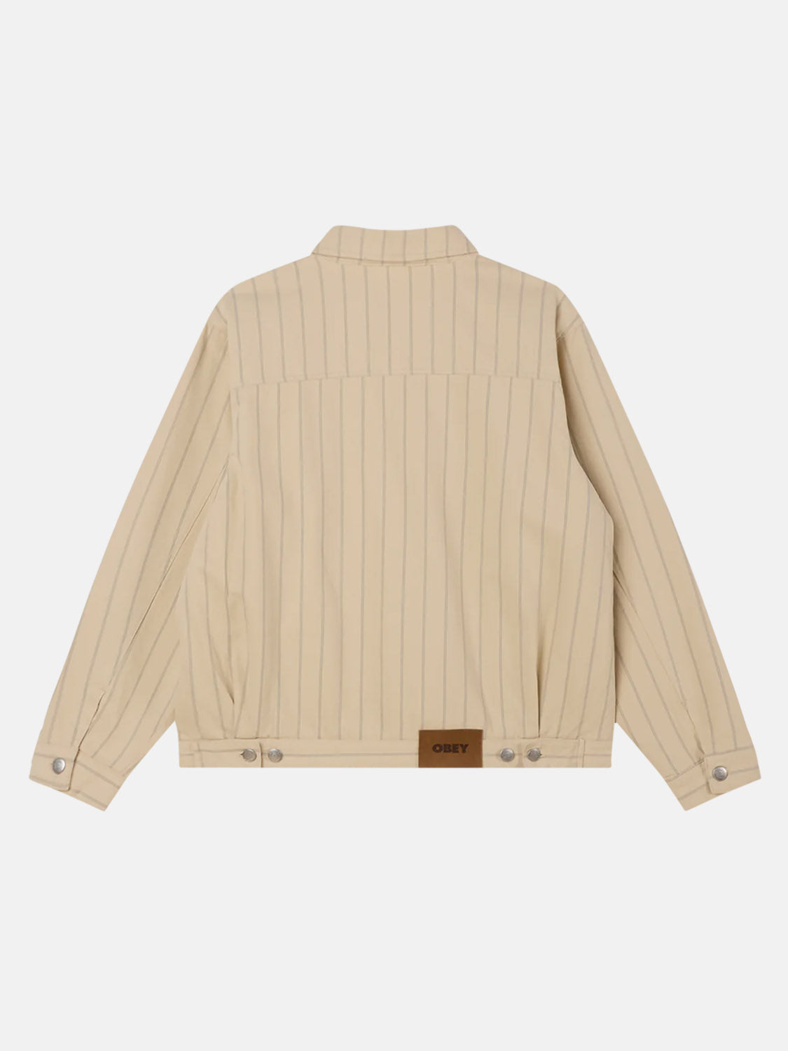 The Obey Stripe Zip Jacket, shown from the back, is beige with thin vertical stripes and a relaxed fit. It has long sleeves, buttoned cuffs, and a brown brand patch at the bottom.