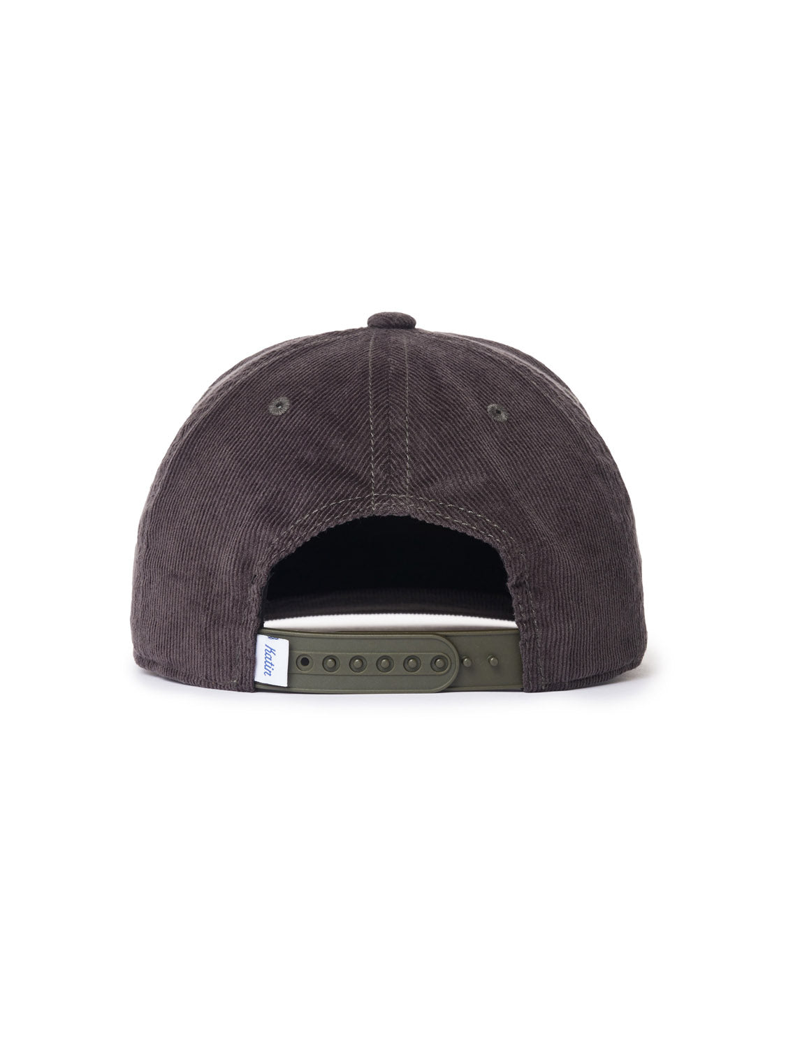 A back view of the Katin Sunflower Corduroy cap, a part of Katins headwear collection, displays a dark gray cotton corduroy with an adjustable green strap and a small white tag with blue text on the left, all set against a plain white background.
