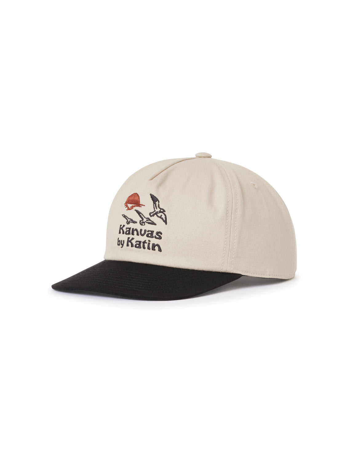 The Katin Sunset Hat is a beige cotton canvas baseball cap with a black brim, featuring embroidered birds and an orange sun along with Kanvas by Katin. It has a snapback closure and is set against a white background.