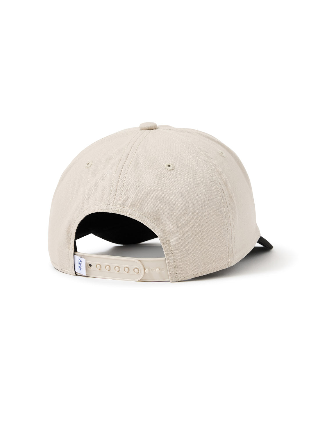 The Katin Sunset Hat, a beige cotton canvas baseball cap, showcases its adjustable snapback closure from the back. Its black brim adds contrast as it elegantly rests on a pristine white surface.