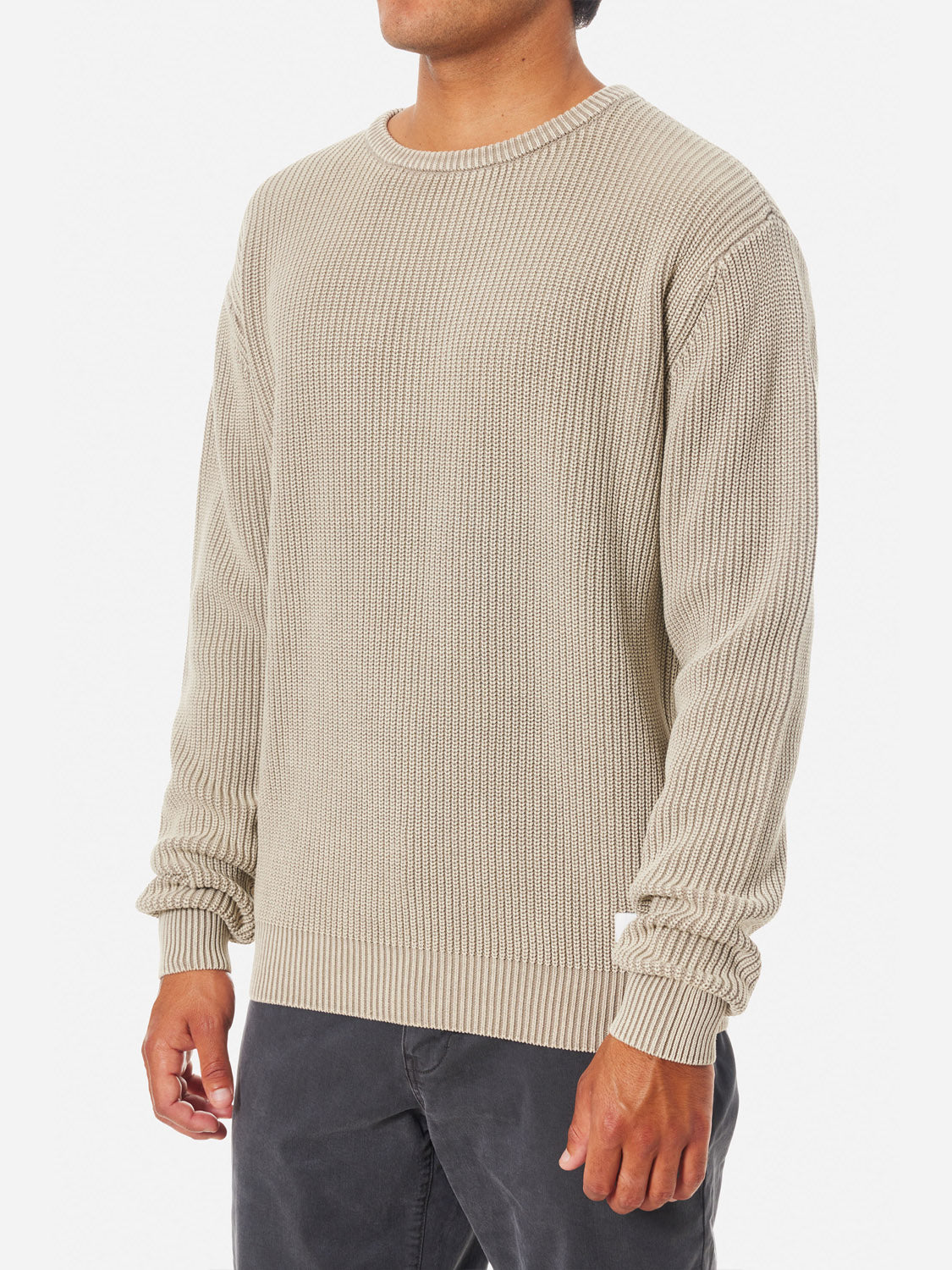 A model is shown from mid-thigh up wearing the Katin Swell Sweater in light beige vintage wash with long sleeves and dark gray pants against a white background; the face is not visible.