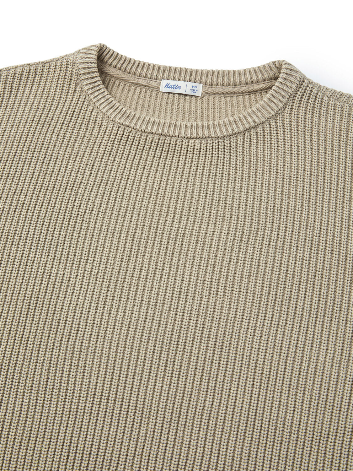 A close-up of the Katin Swell Sweater in beige shows its ribbed knit texture and round neckline, with the detailed weave of the cotton fabric and a small white label inside the collar visible.