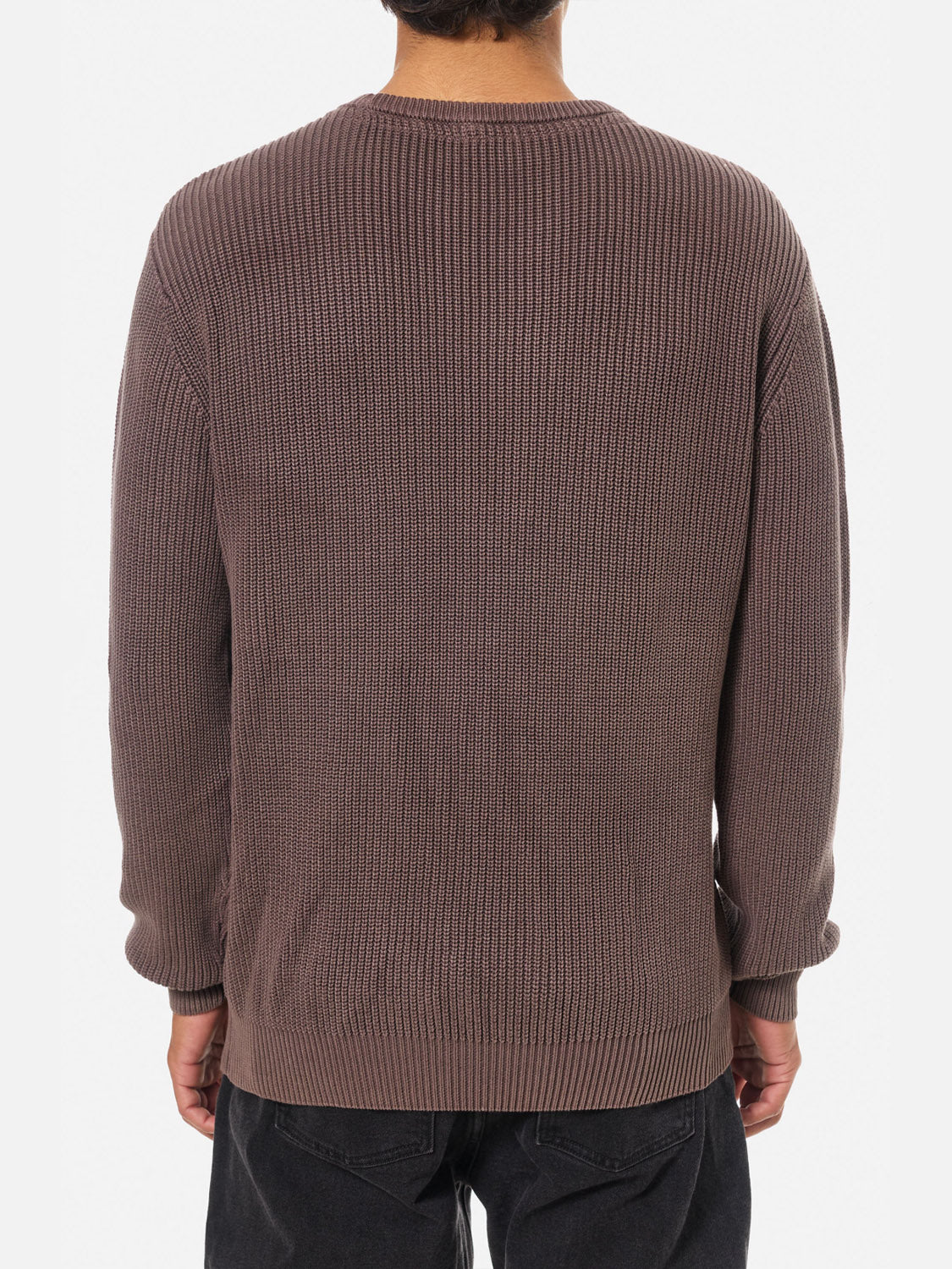A person is seen from behind wearing the Katin Swell Sweater, a loose-fitting, long-sleeved, vintage-wash top, paired with dark pants against a plain white background.