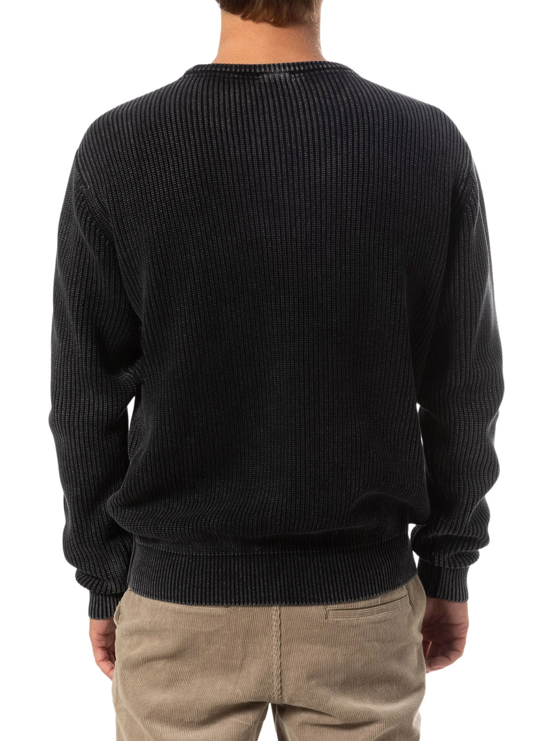 A person is seen from behind in a Katin Swell Sweater with a dark ribbed knit and light brown corduroy pants, set against a white background.