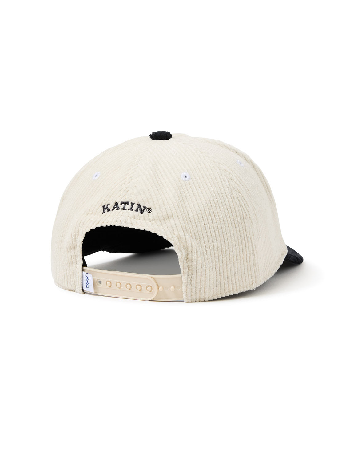 The Katin Swirl Hat is a beige cotton corduroy baseball cap with a black brim, displayed from the rear angle. It includes an adjustable strap with a beige plastic closure and KATIN embroidered in black above the opening, showcasing Katins expert craftsmanship.