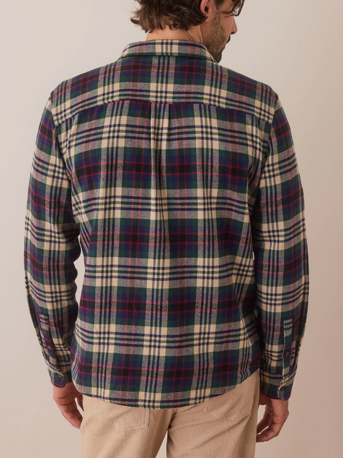 A person with short hair is seen from behind wearing the Marine Layer Tahoe Flannel Shirt made of 100% cotton, featuring shades of blue, white, and red. Its brushed softness complements their light beige pants against a plain background.