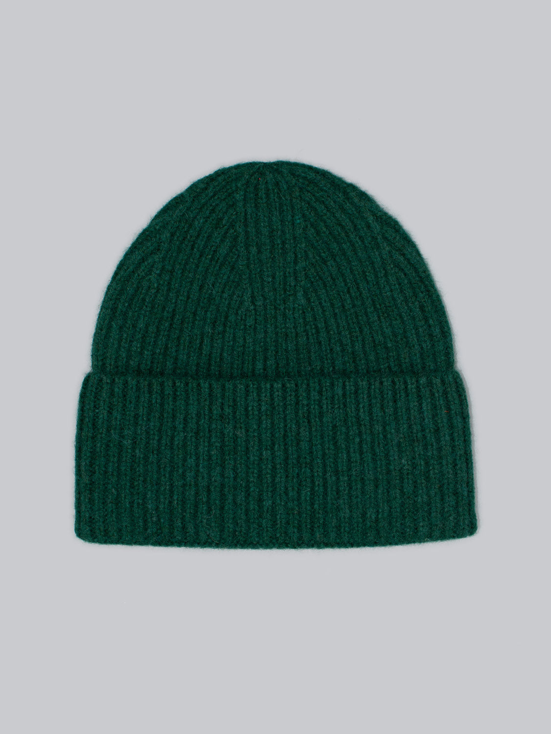 The Telluride Wool Beanie by ID Menswear, a green ribbed hat with a folded brim, is showcased against a plain gray backdrop. It offers natural insulation and a comfortable fit, crafted from soft woolen material.