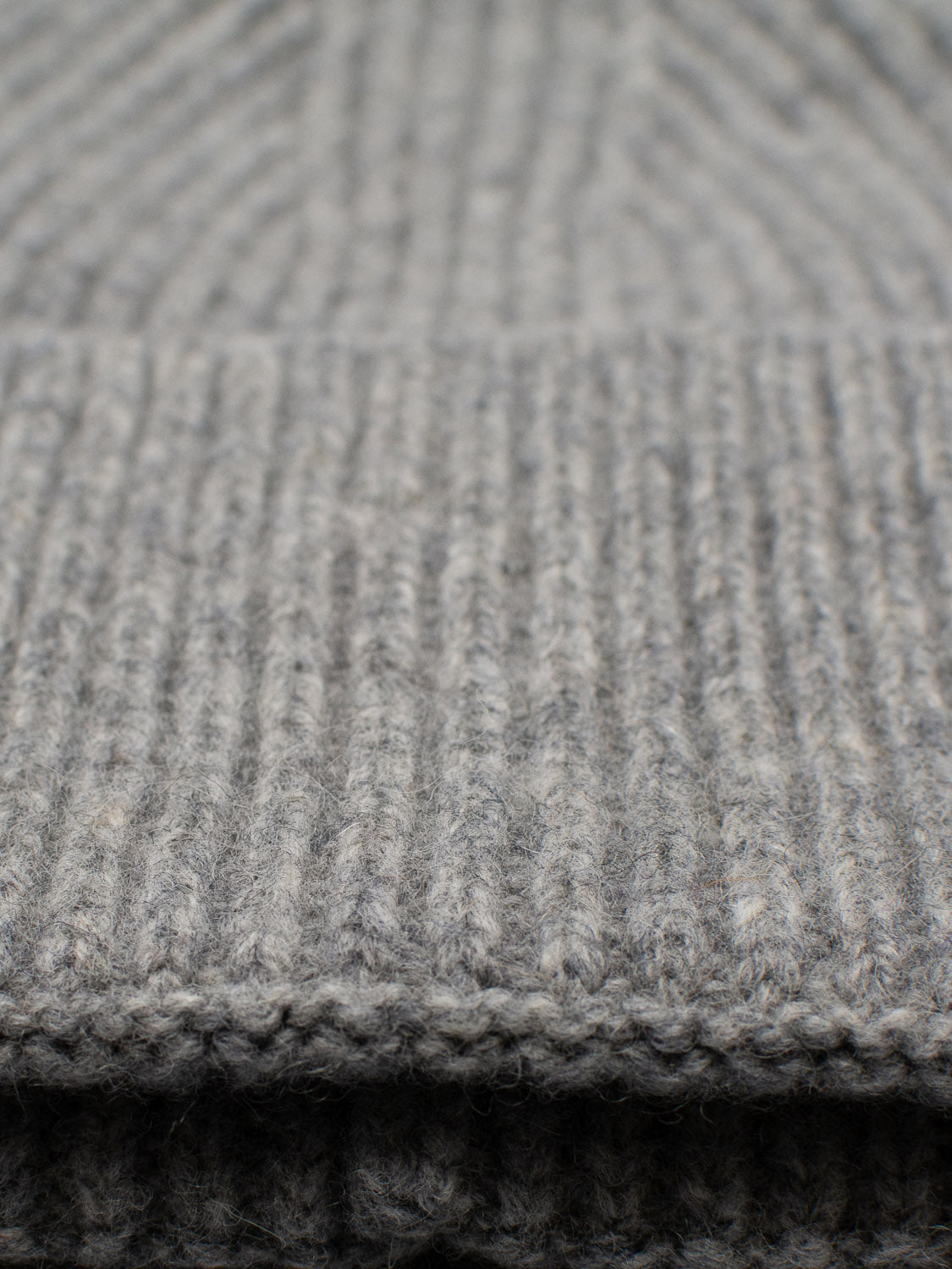 Close-up of the ID Menswear Telluride Wool Beanie in gray, showcasing its ribbed knit texture with layers folded or stacked.