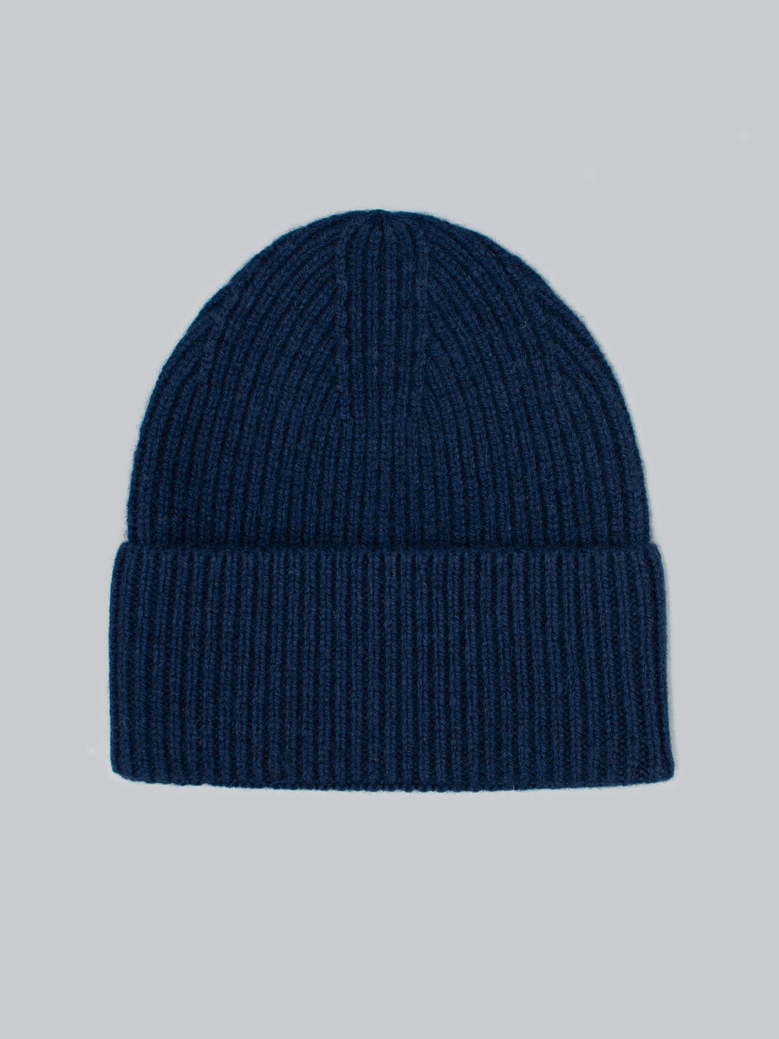 The Telluride Wool Beanie by ID Menswear is showcased on a light gray background. This navy blue beanie features a ribbed texture and a folded brim, providing natural insulation and comfort for a classic, cozy look.