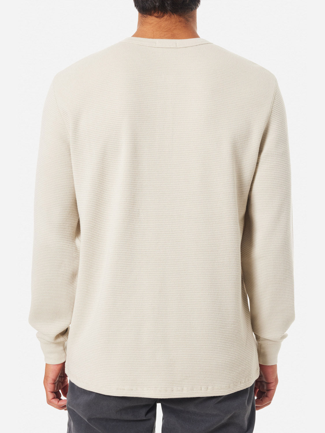 Rear view of a person wearing a Katin Mesa Thermal, a light beige waffle knit shirt by Katin, paired with dark pants. The cotton-polyester blend complements their short dark hair against a plain white background.