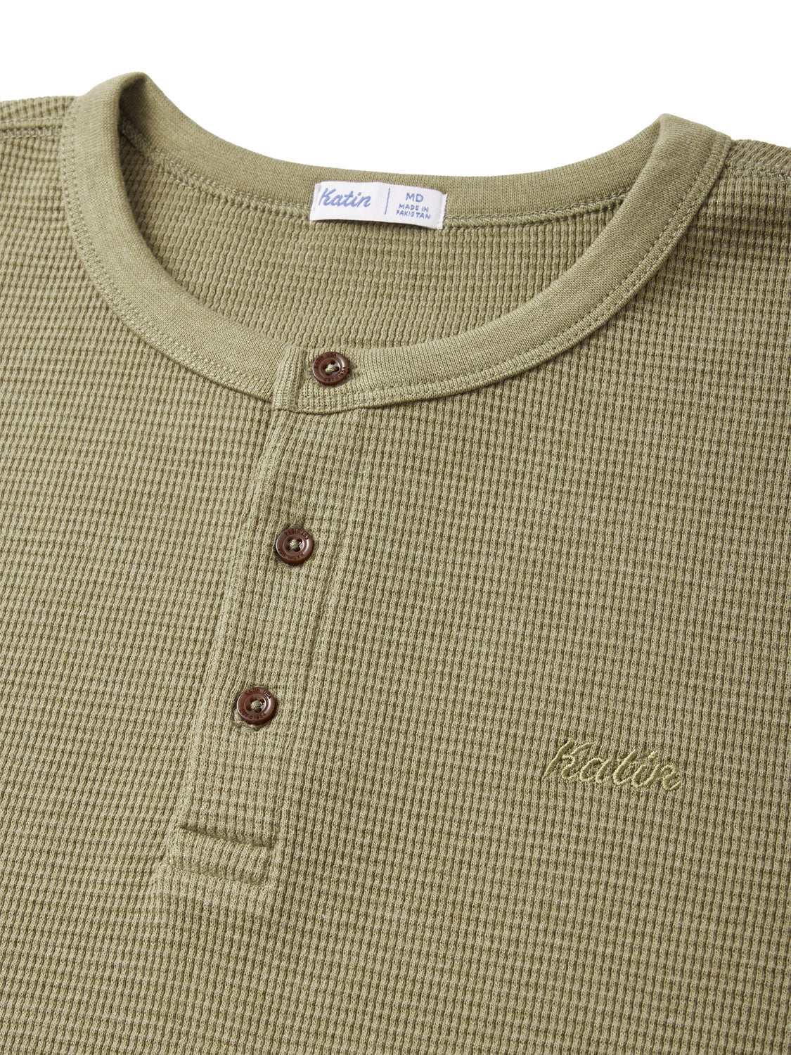The Katin Mesa Thermal is a green waffle-knit Henley with a 3-button placket, round neckline, and a small embroidered logo on the left chest. Made from a cotton-polyester blend, it features branding details and size MD inside the collar.