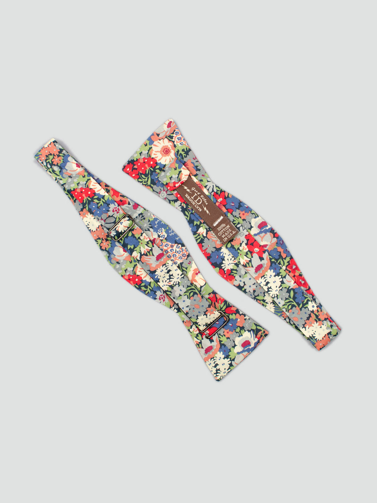 The Liberty of London Tana Lawn™ Thorpe Red Bow Tie by ID Menswear features vibrant red, blue, green, and white floral patterns on cotton. Displayed flat, it showcases its colorful design and detailed ID Menswear brand tag.