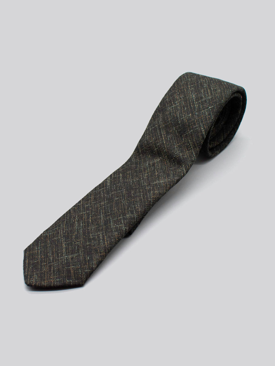 A rolled-up Japanese Printed Ninja Tie by ID Menswear, featuring a subtle textured pattern and handmade in Brooklyn, shown on a plain light grey background.