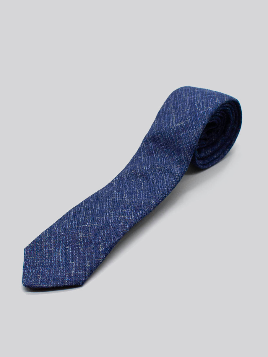 The Japanese Printed Samurai Tie by ID Menswear features a blue textured design with subtle light streaks, handmade from 100% cotton and displayed rolled on a light gray background.