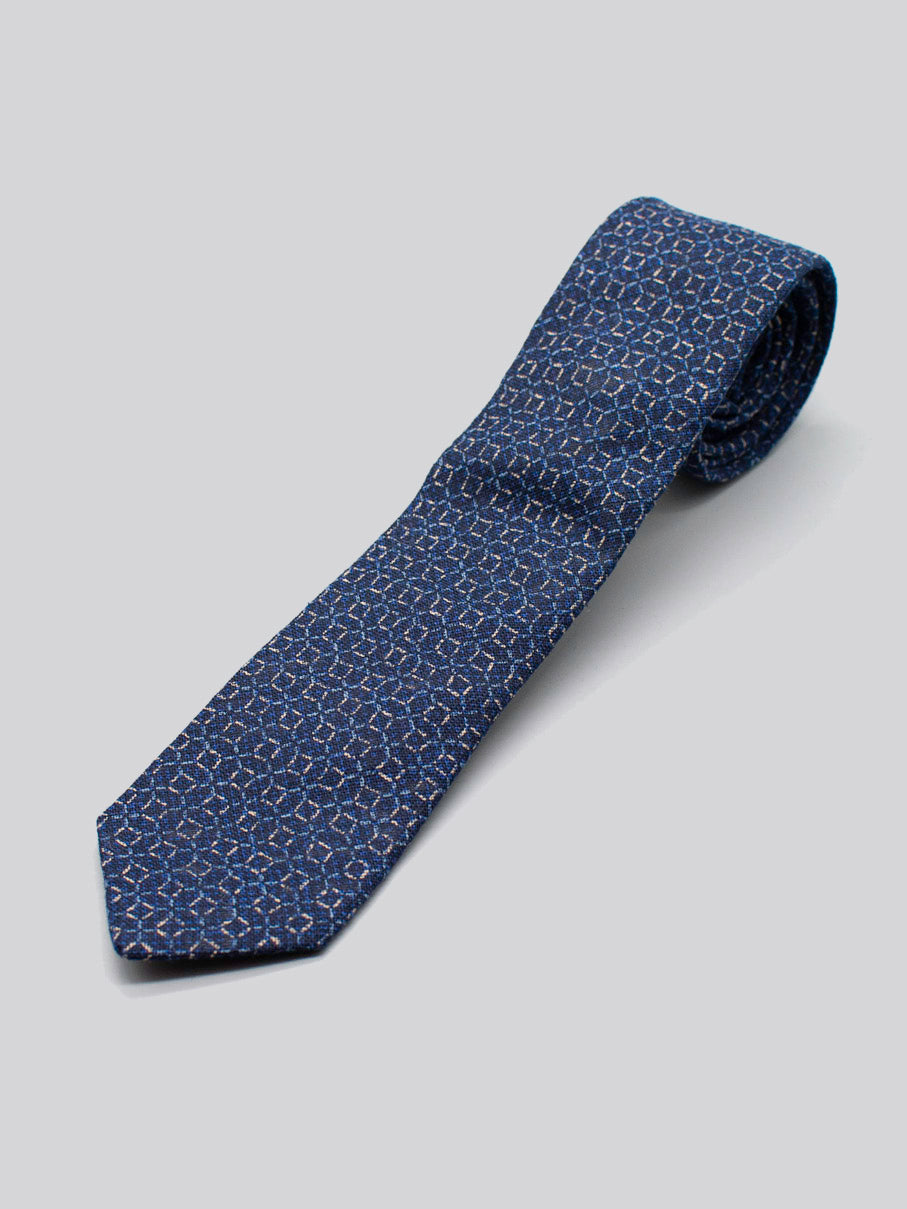 The Japanese Printed Web Tie by ID Menswear is handmade from 100% cotton with a blue base and subtle light blue and pink geometric patterns, shown on a plain light gray background.