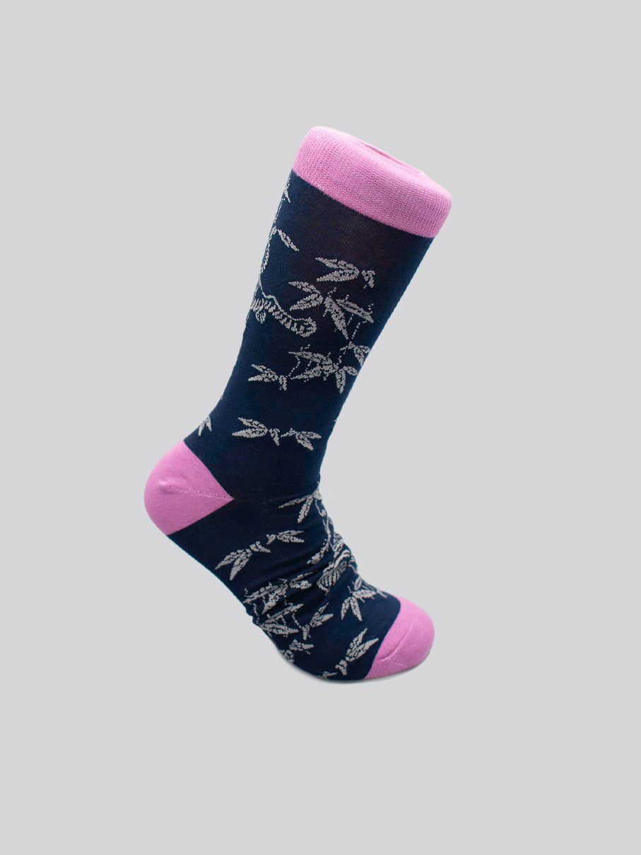The Tiger Graphic Sock by ID Menswear is a single navy blue sock with light pink heel, toe, and cuff, made from soft combed cotton and featuring a white bamboo leaf pattern, shown on a light gray background.