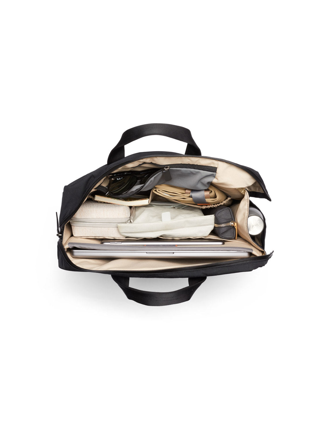 An overhead view of the Bellroy Tokyo Work Bag - 20L, open and neatly organized with cables, a water bottle, a rolled-up cloth, notebook, documents, and other accessories in separate compartments—including a dedicated 16” laptop sleeve.