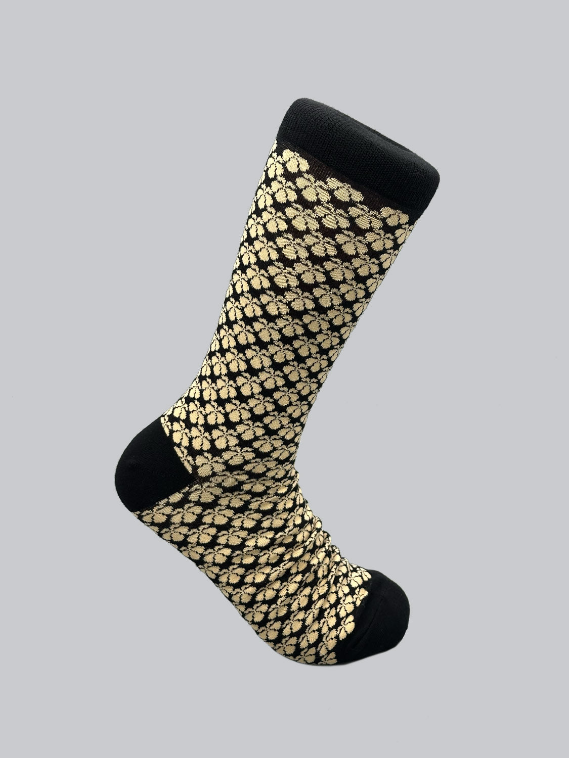 The Toyo Graphic Socks by ID Menswear showcase a Jacquard pattern of beige lions on a black background. Featuring a solid black toe, heel, and cuff, these combed cotton socks highlight Japanese artistry against a subtle grey backdrop.