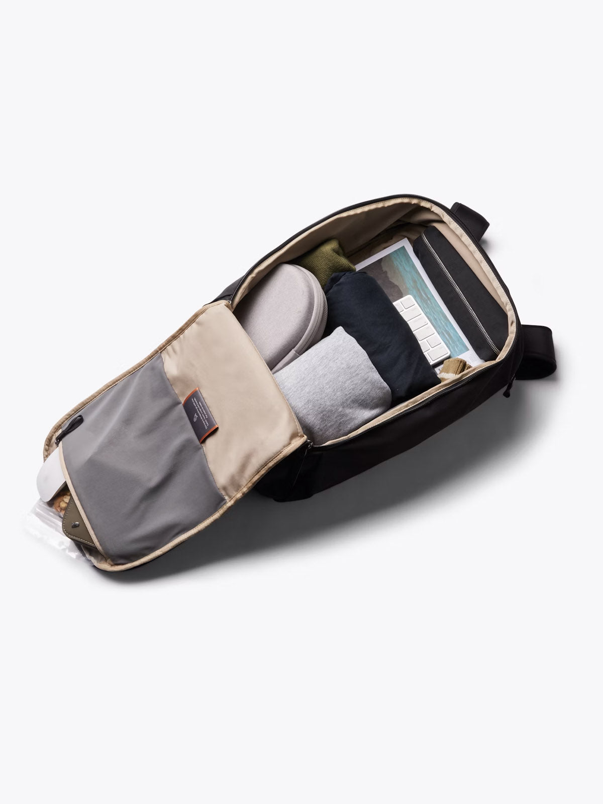 The Bellroy Transit Workpack - 20L, shown unzipped and flat, neatly holds clothes, shoes, a glasses case, and a tablet or slim laptop in its sleeve—its organized compartments make it the ideal minimalist work bag.