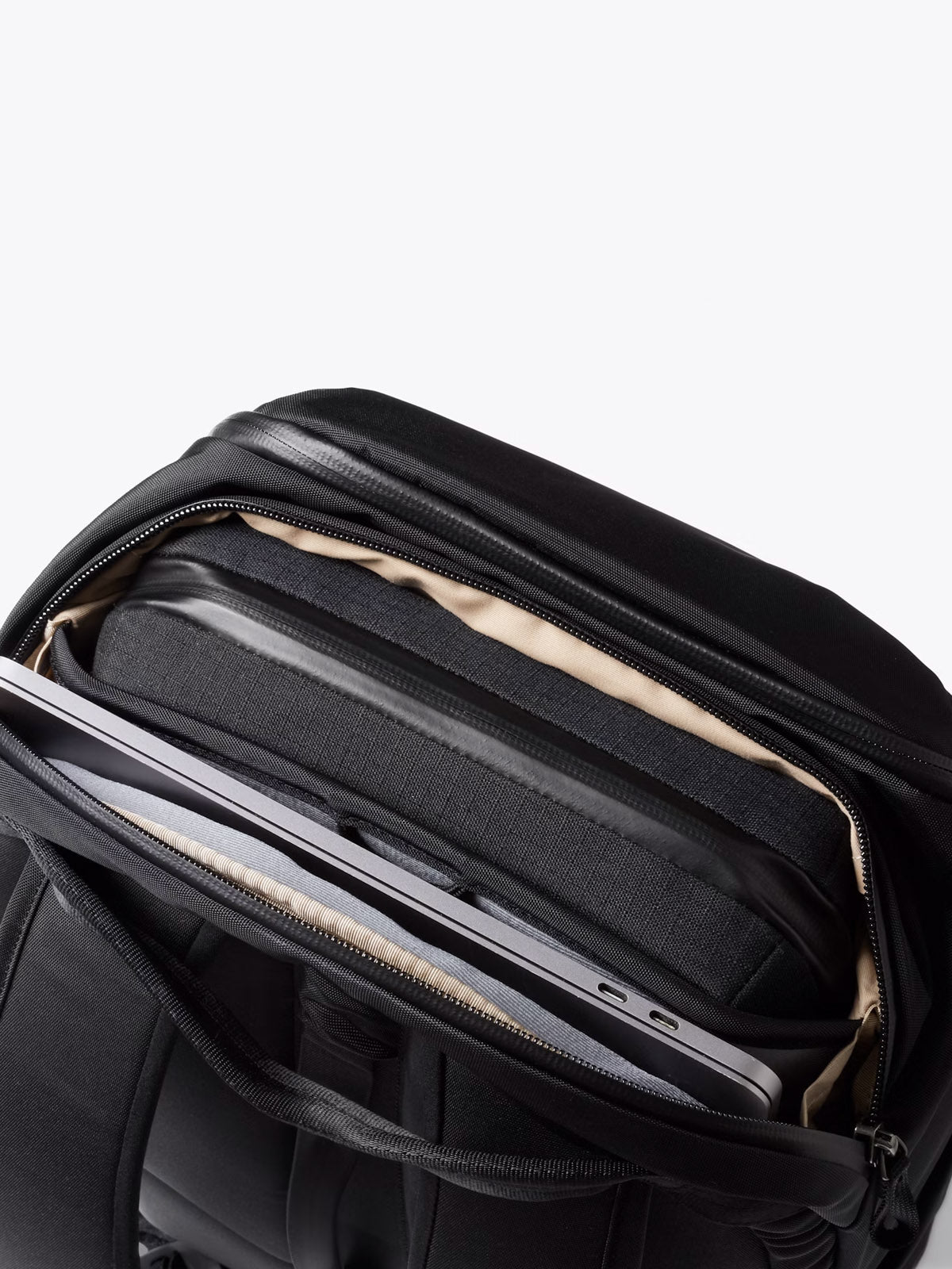 The Bellroy Transit Workpack - 20L is open, revealing a minimalist black design with multiple compartments neatly organizing a laptop, tablet, and accessories in dedicated sleeves.