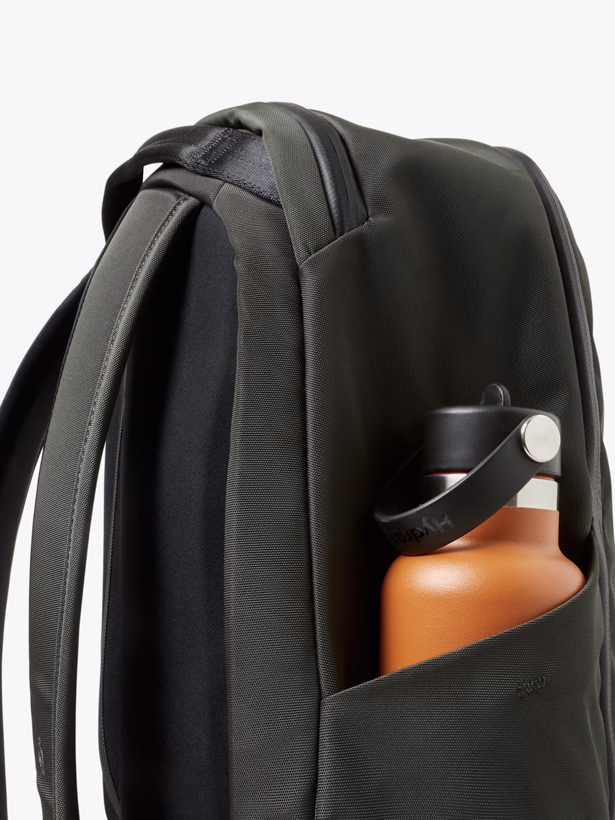 The Bellroy Transit Workpack - 20L is a dark minimalist backpack with a side pocket for an orange water bottle (black handle, silver cap) and a dedicated laptop sleeve, shown against a plain light background.