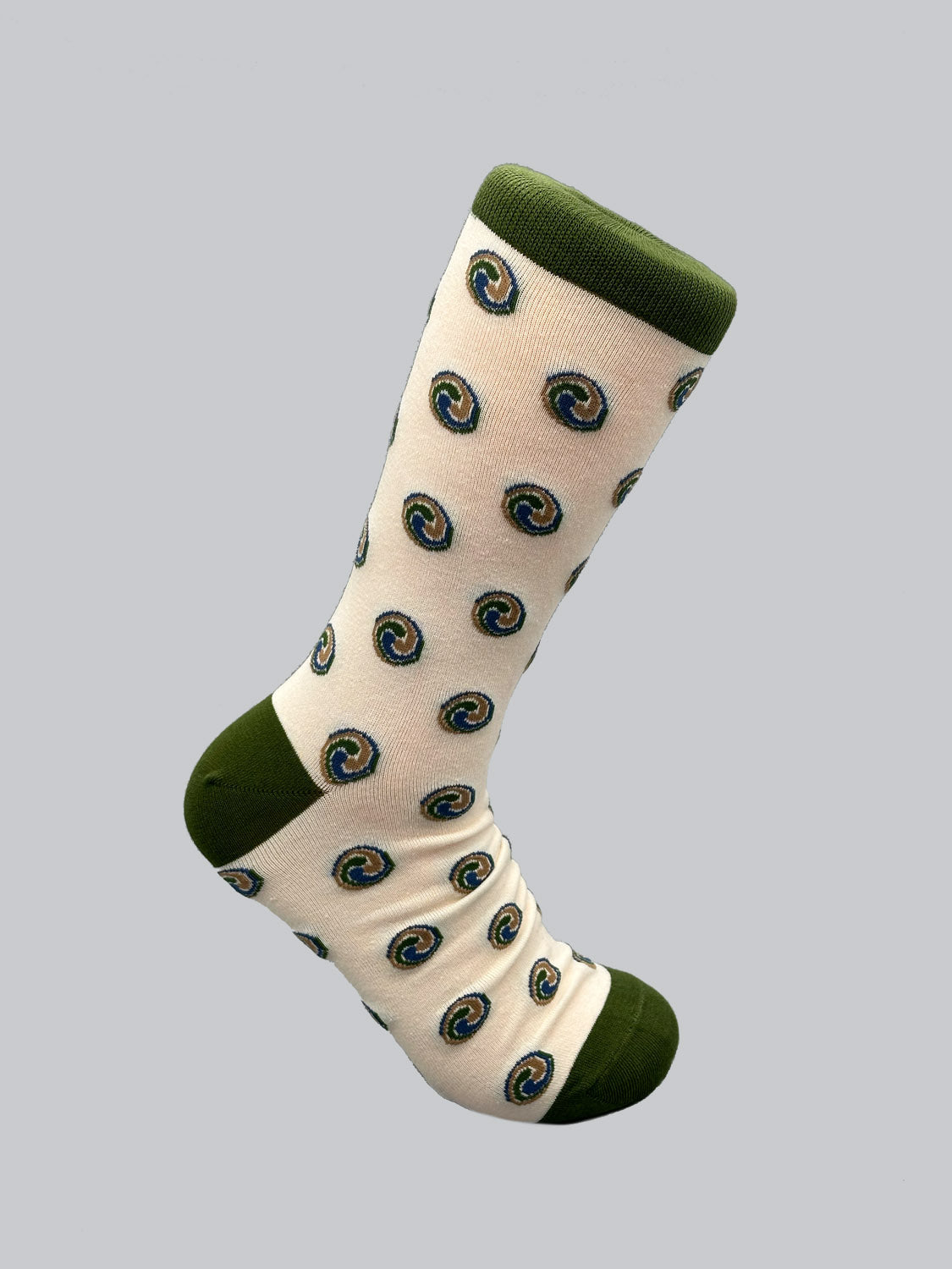 A single crew-length sock on a grey background. Expertly crafted from combed cotton, the ID Menswear Trinity Graphic Socks are white with green and blue Jacquard spirals and feature a green heel, toe, and cuff for added style.
